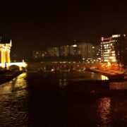 Pamje panoramike e qendrës së Shkupit gjatë natës, me Urën e Gurit dhe ndërtesat pranë lumit Vardar