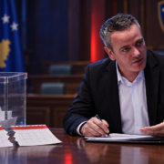 Arben Gashi pranë një urne votimi dhe dy fletëve të grisura të kalendarit