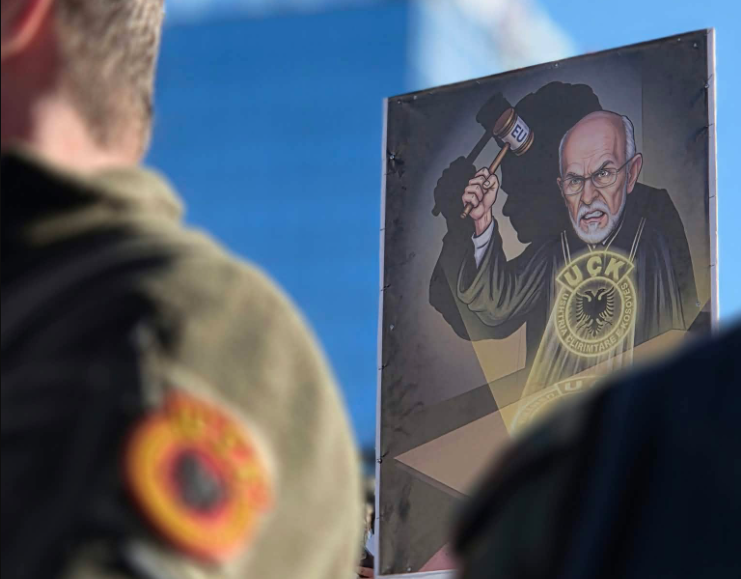 Pankartë në protestë: Charles Smith me çekiç të BE-së dhe siluetën e Kurtit